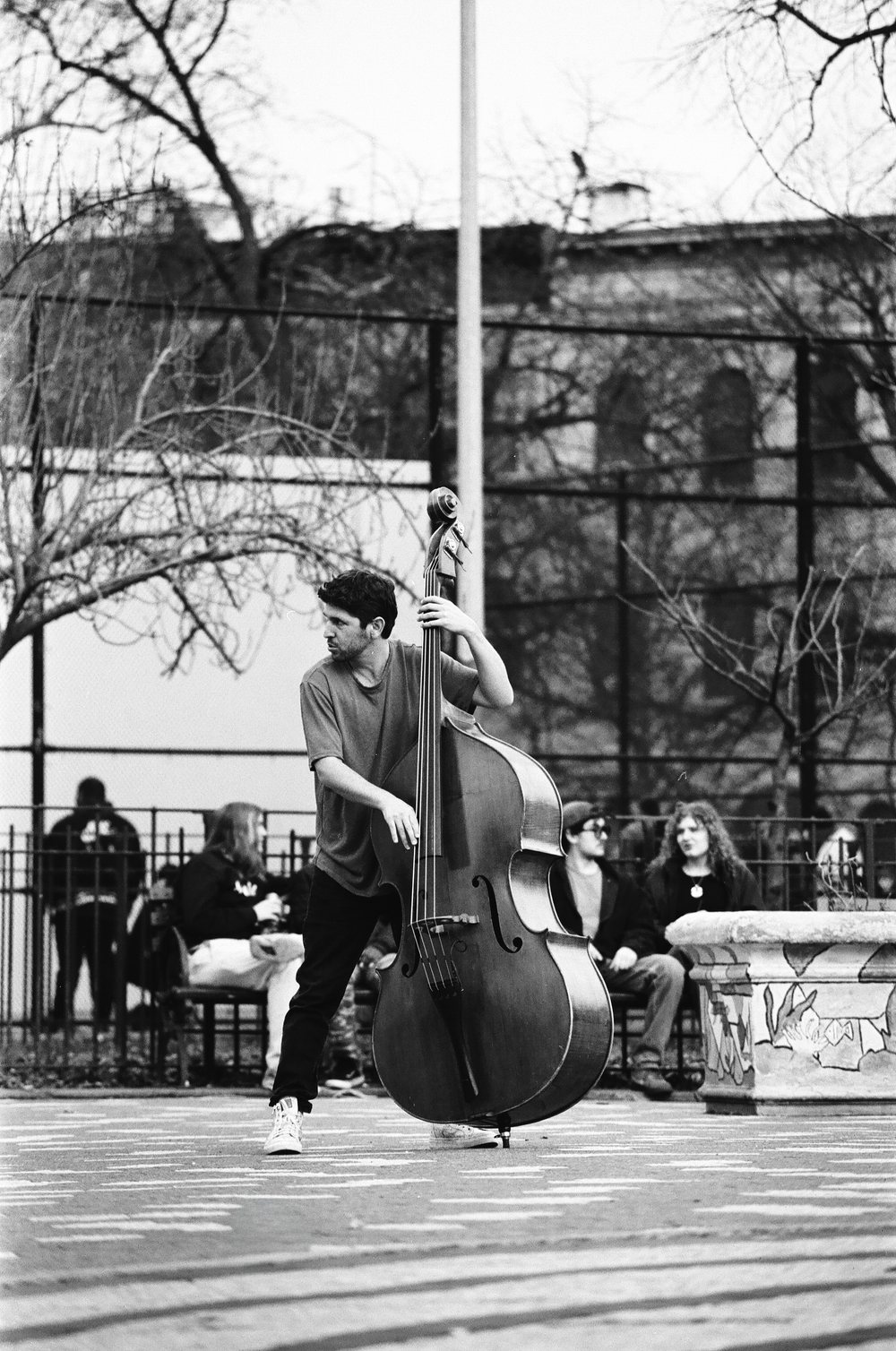 Tal Mashiach playing double bass in a Brooklyn playground